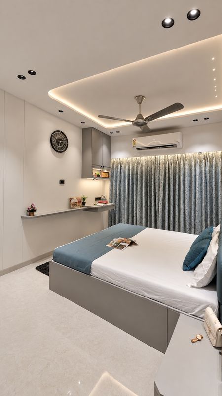 Bedroom with a floating study ledge, a grey wall cabinet, a cove-lit ceiling and blue leaf-print curtains
