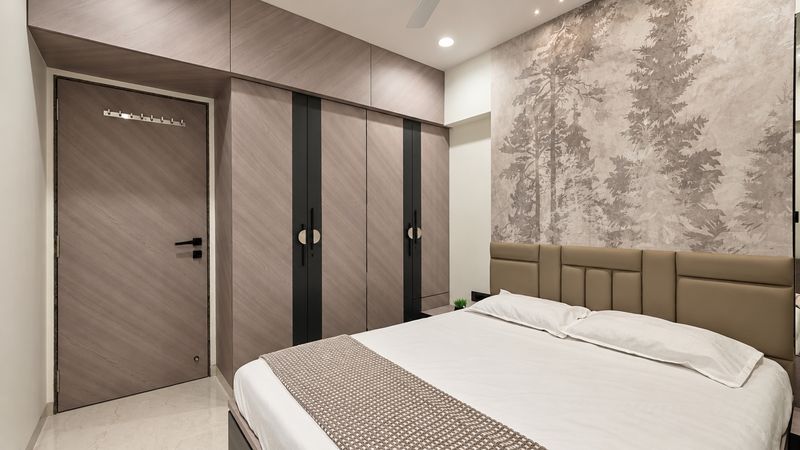 Second bedroom with a forest-print feature wall, a panelled headboard and a chevron wood wardrobe beside the door