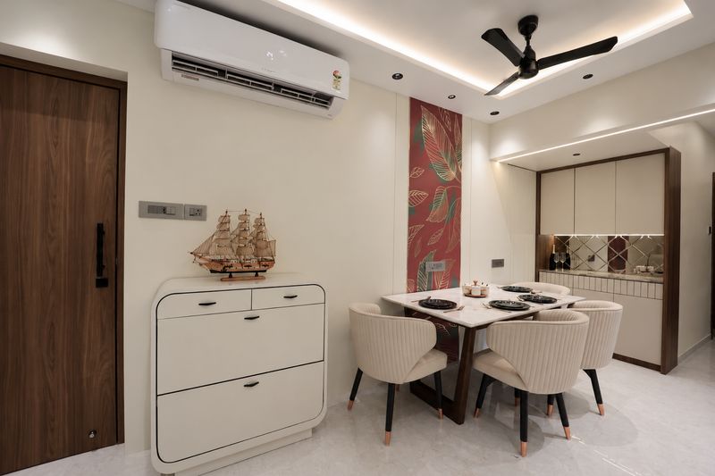 Dining area with a round table, cream chairs, a wooden shoe cabinet and a leaf-pattern wall panel