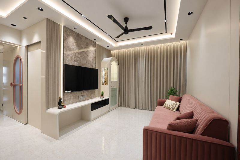 Living room with a stone-look television wall, cove lighting and a coral sofa