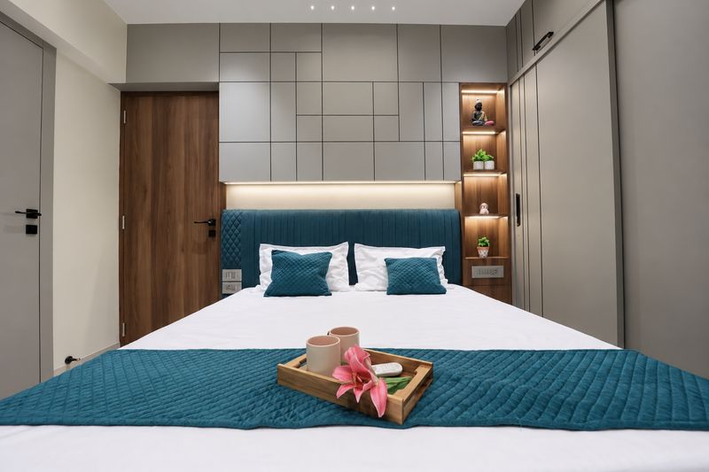 Master bedroom with a teal padded headboard and a wooden tray on the bed
