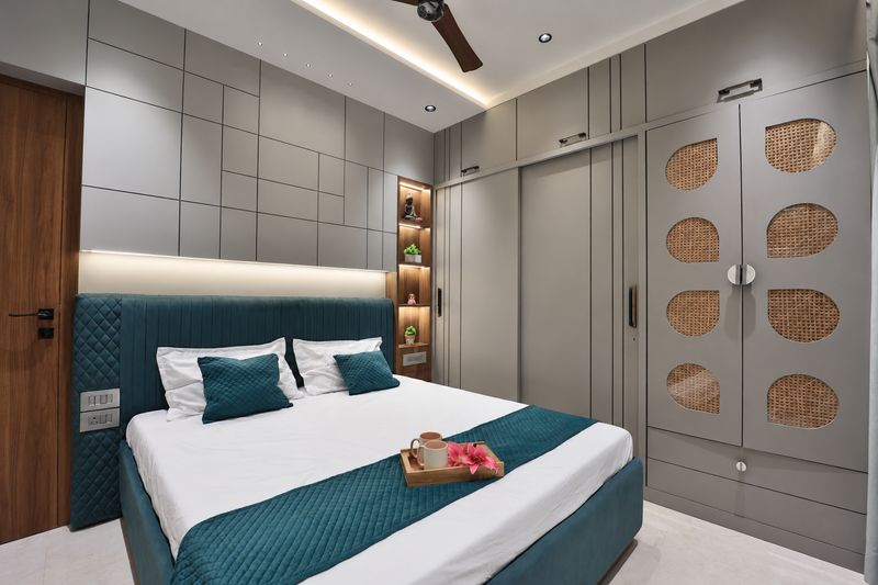 Master bedroom with a teal bed, a cane-panel wardrobe and lit shelves