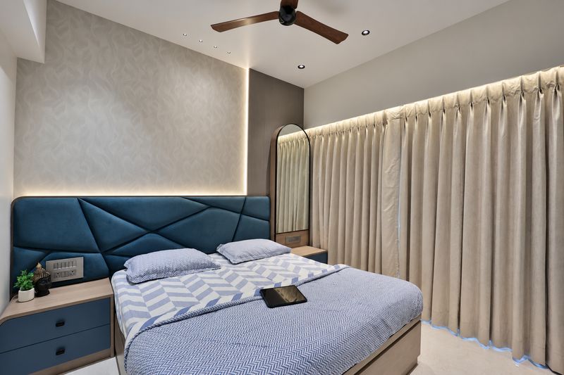 Second bedroom with a blue geometric headboard and cream curtains