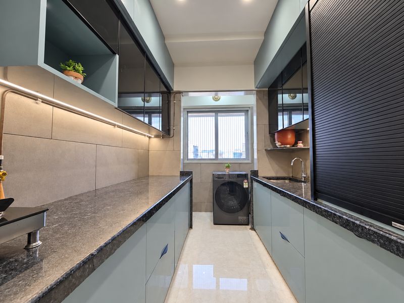 Galley kitchen with teal cabinets, a dark granite counter and warm under-cabinet light