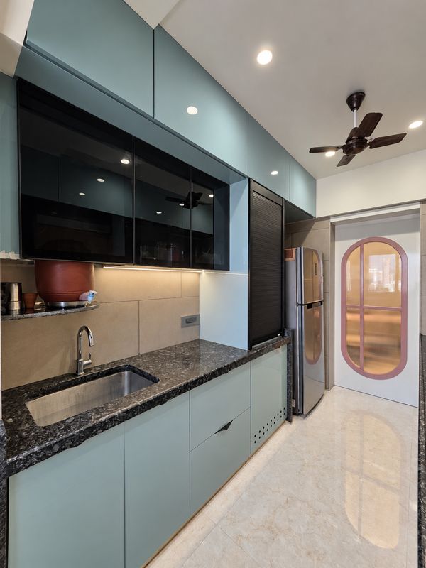 Kitchen with teal upper cabinets, a refrigerator and an arched glass door beyond