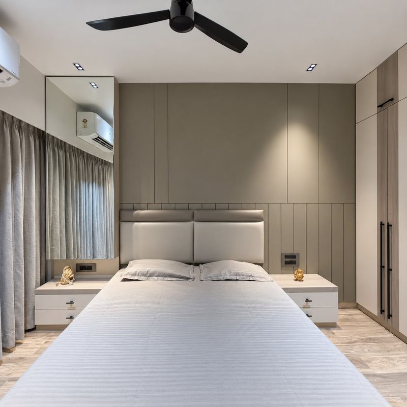 Bedroom with a soft leather-look headboard, a grey panelled wall, fitted wardrobes and bedside tables