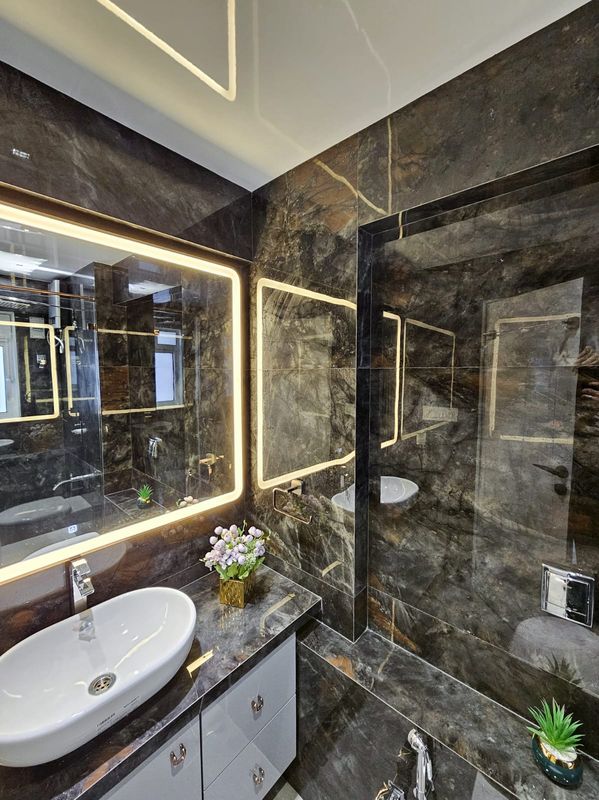 Bathroom with dark stone walls and an illuminated mirror