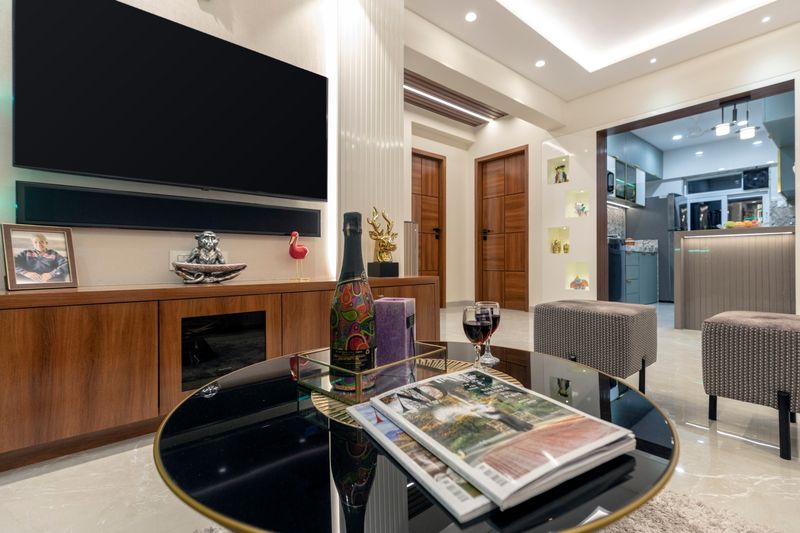Living room with a round black glass coffee table, a wall-mounted TV over a walnut unit, and the kitchen beyond