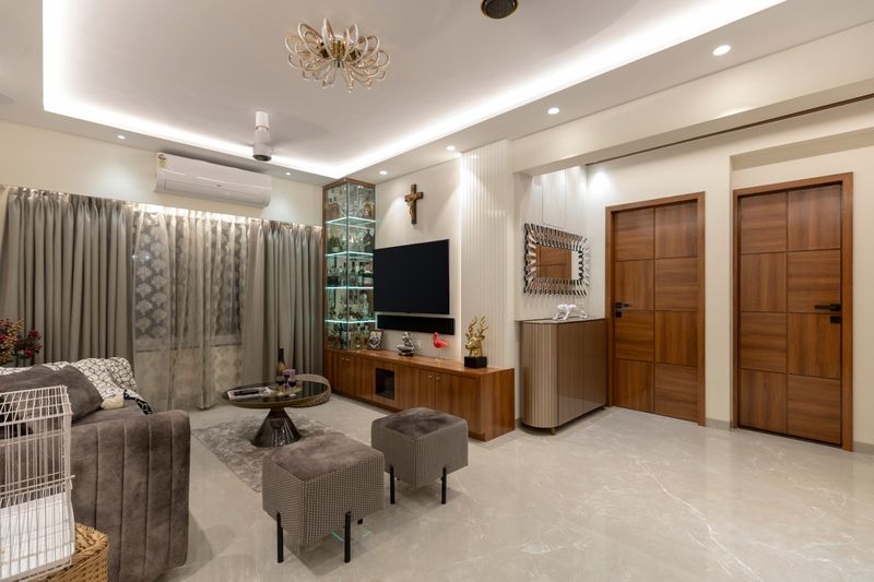 Living room with a grey sofa, a lit glass bar cabinet beside the TV, a fluted sideboard and walnut doors