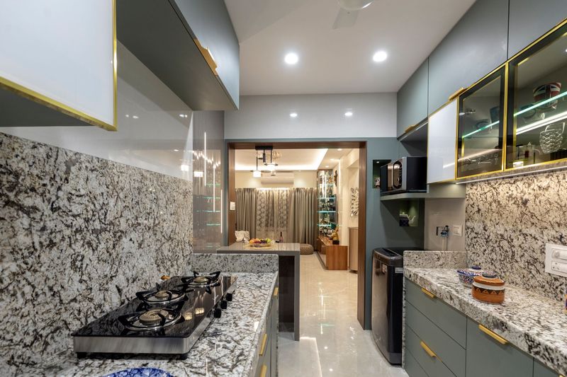 Kitchen with sage-green cabinets, brass-trimmed glass uppers and granite counters, looking through to the living room