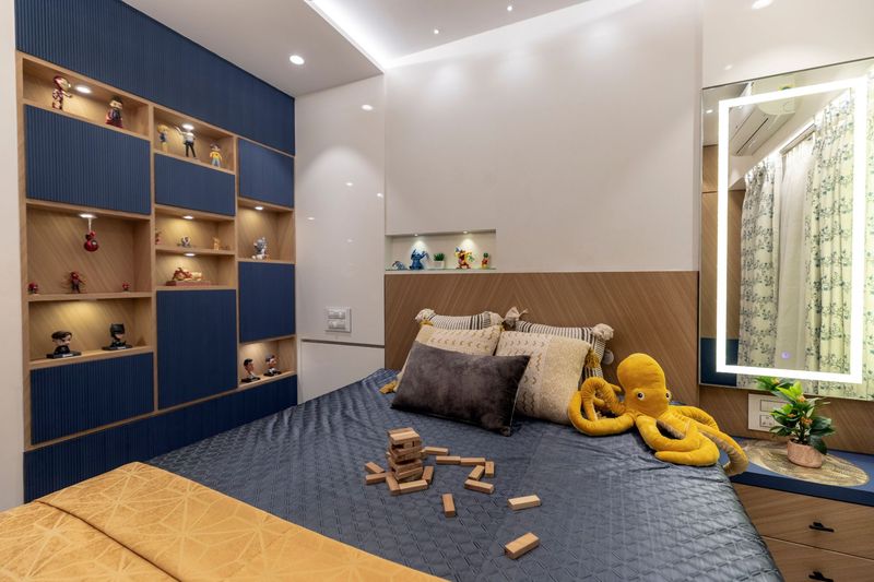 Kids' room with a blue fluted wall of display shelves for figurines, a chevron wood headboard and a lit mirror