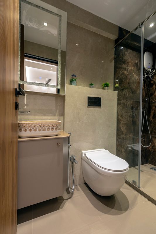 Bathroom with a gold-patterned vessel basin on a taupe vanity, a jewelled mirror, wall-hung WC and a glass shower